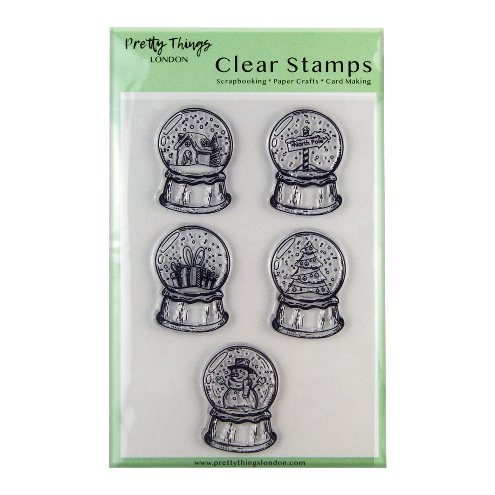 A set of Pretty Things London clear stamps for scrapbooking, paper crafts, and card making. The set includes five different snow globe designs, featuring a house, North Pole sign, gift box, decorated Christmas tree, and snowman. Each snow globe is detailed and festive, packaged in a clear, green-tinted plastic cover.